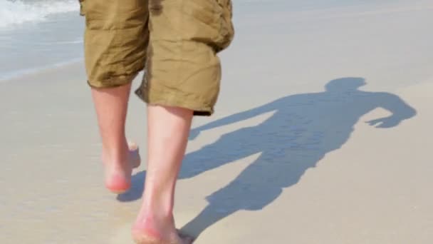 Voeten lopen op de golven, voetafdrukken in het zand van de zee — Stockvideo