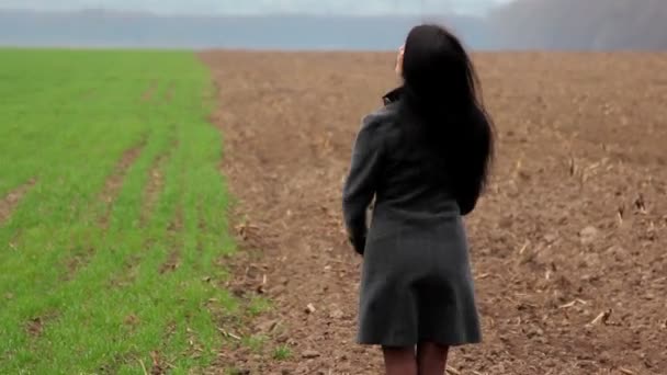 Chica en un campo mirando pensativamente a la distancia, chica joven en un campo — Vídeo de stock