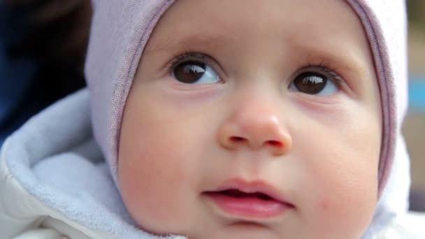 Un piccolo bambino carino sta guardando nella macchina fotografica. Il bambino si guarda intorno guardando nella fotocamera . — Video Stock