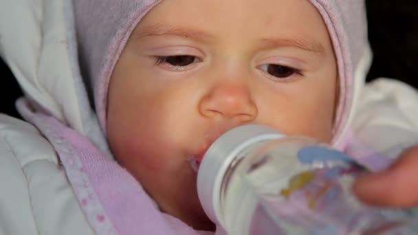 Un piccolo bambino carino che beve dai capezzoli. Un piccolo bambino carino si tiene per mano il ciuccio con acqua . — Video Stock