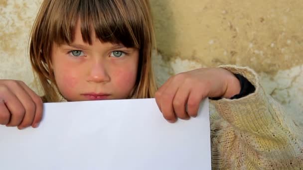 Niño sosteniendo una hoja de papel.Niño sosteniendo una hoja de papel.Sobre el fondo de una vieja pared — Vídeos de Stock