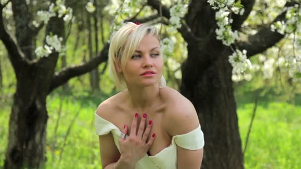 Jovem menina bonita posando para a câmera no jardim de floração primavera, menina bonita no jardim de primavera — Vídeo de Stock