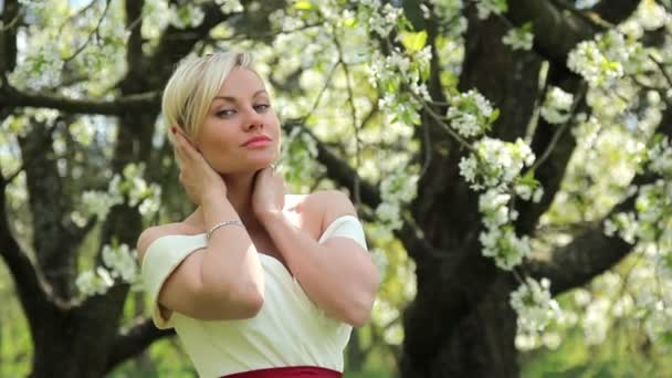 Joven hermosa chica posando en la cámara en el jardín de primavera floreciente, Hermosa chica en el jardín de primavera — Vídeos de Stock