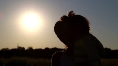 genç anne holding bebek çocuk doğası üzerine sunset.young anne, kollarını.