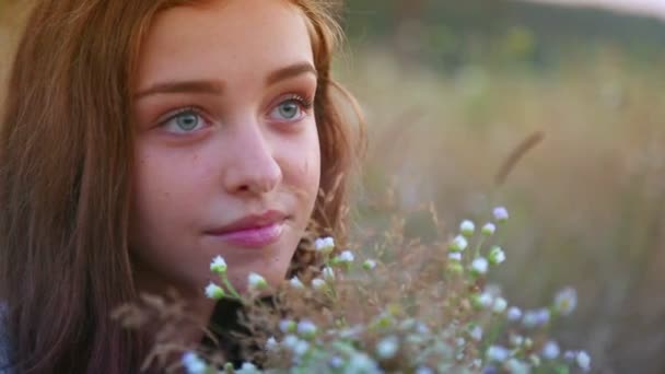 Retrato de menina.Menina adolescente com um buquê de flores silvestres no campo . — Vídeo de Stock