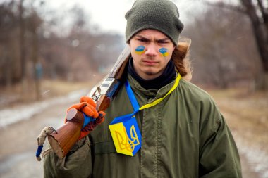 Kontrol noktasında silahlı Ukraynalı genç bir çocuk. Bir Ukraynalı vatansever köyün girişini koruyor..