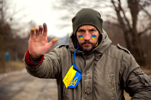 A Ukrainian man with a weapon at a checkpoint. A Ukrainian patriot guards the entrance to his village. 