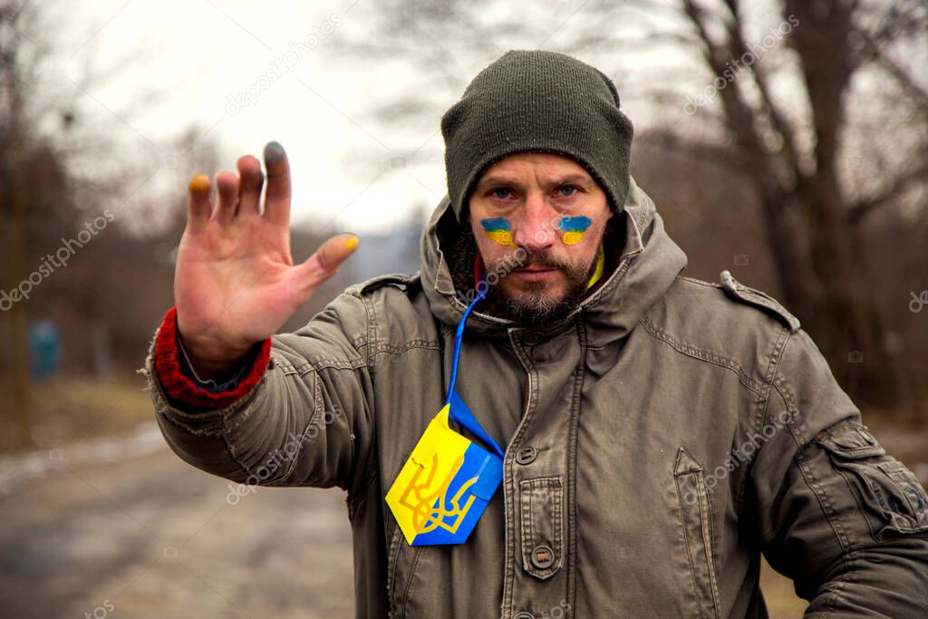 A Ukrainian man with a weapon at a checkpoint. A Ukrainian patriot guards the entrance to his village. 