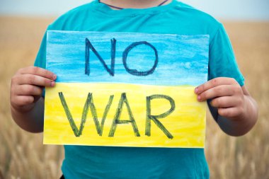 Buğday tarlasında bir çocuk savaşa karşı bir bayrak tutar. Ukraynalı çocuk savaşa karşı. Çocuk vatanseverliği. Yüzü olmayan çocuklar. 