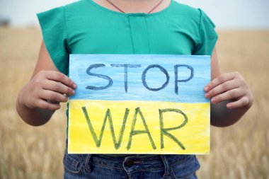 Buğday tarlasında bir çocuk savaşa karşı bir bayrak tutar. Ukraynalı çocuk savaşa karşı. Çocuk vatanseverliği. Yüzü olmayan çocuklar. 