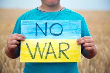 Buğday tarlasında bir çocuk savaşa karşı bir bayrak tutar. Ukraynalı çocuk savaşa karşı. Çocuk vatanseverliği. Yüzü olmayan çocuklar. 