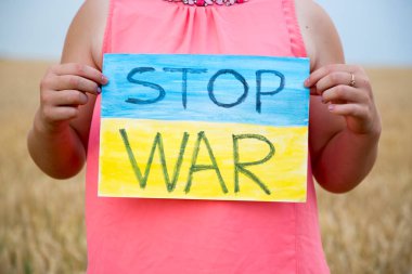 Buğday tarlasında bir çocuk savaşa karşı bir bayrak tutar. Ukraynalı çocuk savaşa karşı. Çocuk vatanseverliği. Yüzü olmayan çocuklar. 