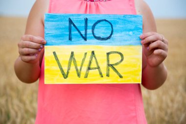 Buğday tarlasında bir çocuk savaşa karşı bir bayrak tutar. Ukraynalı çocuk savaşa karşı. Çocuk vatanseverliği. Yüzü olmayan çocuklar. 