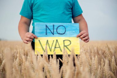 Buğday tarlasında bir çocuk savaşa karşı bir bayrak tutar. Ukraynalı çocuk savaşa karşı. Çocuk vatanseverliği. Yüzü olmayan çocuklar. 