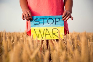 Buğday tarlasında bir çocuk savaşa karşı bir bayrak tutar. Ukraynalı çocuk savaşa karşı. Çocuk vatanseverliği. Yüzü olmayan çocuklar. 