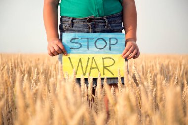 Buğday tarlasında bir çocuk savaşa karşı bir bayrak tutar. Ukraynalı çocuk savaşa karşı. Çocuk vatanseverliği. Yüzü olmayan çocuklar. 