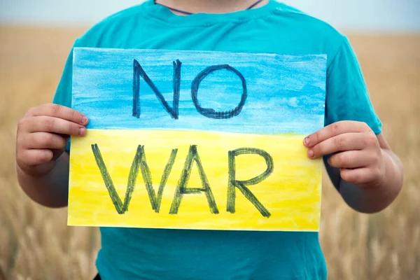 Buğday tarlasında bir çocuk savaşa karşı bir bayrak tutar. Ukraynalı çocuk savaşa karşı. Çocuk vatanseverliği. Yüzü olmayan çocuklar. 