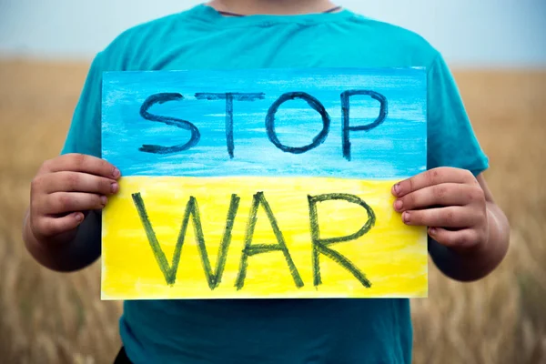 Buğday tarlasında bir çocuk savaşa karşı bir bayrak tutar. Ukraynalı çocuk savaşa karşı. Çocuk vatanseverliği. Yüzü olmayan çocuklar. 
