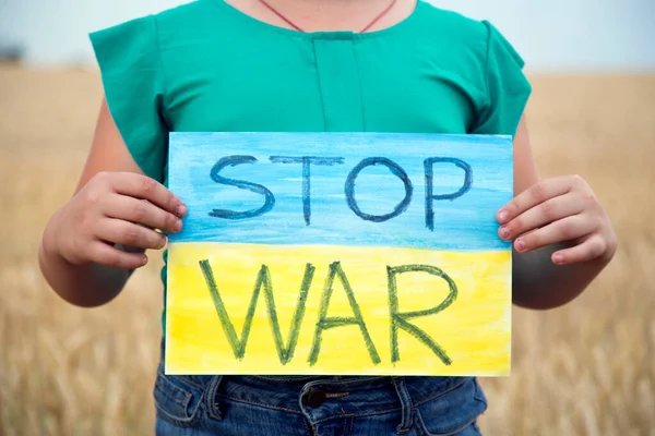 Buğday tarlasında bir çocuk savaşa karşı bir bayrak tutar. Ukraynalı çocuk savaşa karşı. Çocuk vatanseverliği. Yüzü olmayan çocuklar. 