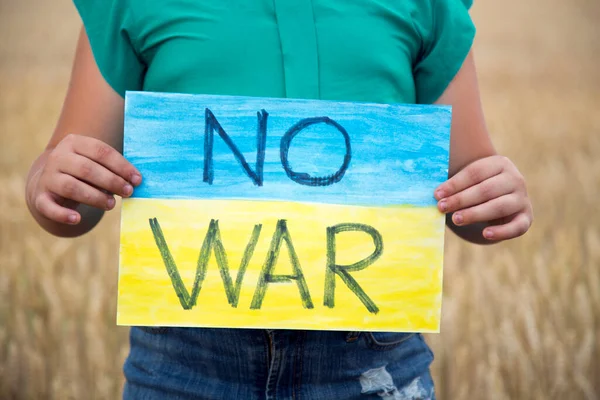 Buğday tarlasında bir çocuk savaşa karşı bir bayrak tutar. Ukraynalı çocuk savaşa karşı. Çocuk vatanseverliği. Yüzü olmayan çocuklar. 