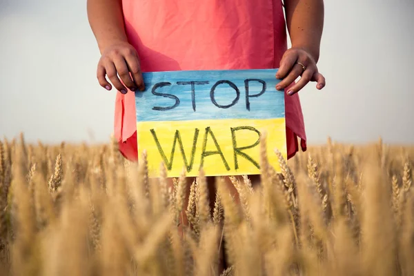 Buğday tarlasında bir çocuk savaşa karşı bir bayrak tutar. Ukraynalı çocuk savaşa karşı. Çocuk vatanseverliği. Yüzü olmayan çocuklar. 