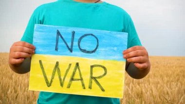 Buğday tarlasında bir çocuk savaşa karşı bir bayrak tutar. Ukraynalı çocuk savaşa karşı. Çocuk vatanseverliği. Yüzü olmayan çocuklar. 