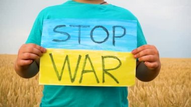 Buğday tarlasında bir çocuk savaşa karşı bir bayrak tutar. Ukraynalı çocuk savaşa karşı. Çocuk vatanseverliği. Yüzü olmayan çocuklar. 