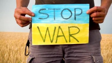Erkek eller Ukrayna 'daki savaşa karşı bir yazı olan bir posteri tutuyor. Ukrayna 'da savaş. Savaş yok. Savaşı Durdur. 
