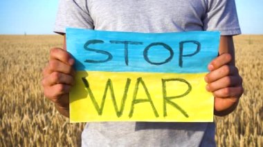 Erkek eller Ukrayna 'daki savaşa karşı bir yazı olan bir posteri tutuyor. Ukrayna 'da savaş. Savaş yok. Savaşı Durdur. 
