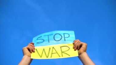 Erkek eller Ukrayna 'da gökyüzüne karşı yapılan savaşa karşı bir poster tutuyor. Savaş yok. Ukrayna 'daki savaşı durdurun.. 
