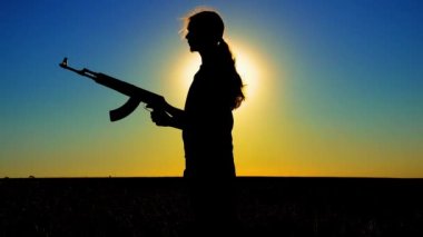 Ukrayna Savaşı. Tarlada Kalaşnikov saldırı tüfeği taşıyan genç bir adam. Kalaşnikof tüfekli bir adamın silueti. Savaş konsepti, terörizm, Ukrayna 'ya karşı saldırı. 