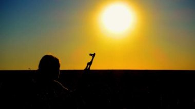 Ukrayna Savaşı. Tarlada Kalaşnikov saldırı tüfeği taşıyan genç bir adam. Kalaşnikof tüfekli bir adamın silueti. Savaş konsepti, terörizm, Ukrayna 'ya karşı saldırı. 