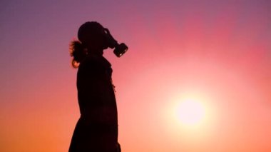 Apocalypse. A man takes off his gas mask at sunset. A stalker on a scorched earth after a nuclear war takes off his gas mask. Concept of mass destruction, apocalypse, human extinction. 