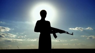 Ukrayna Savaşı. Kalaşnikof tüfekli genç bir kadın sahada eğitim görüyor. Kalaşnikof tüfekli bir kızın silueti. Savaş konsepti, terörizm, Ukrayna 'ya karşı saldırı. 