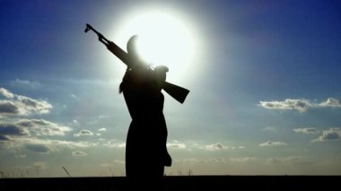 Ukrayna Savaşı. Kalaşnikof tüfekli genç bir kadın sahada eğitim görüyor. Kalaşnikof tüfekli bir kızın silueti. Savaş konsepti, terörizm, Ukrayna 'ya karşı saldırı. 