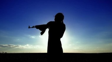 Ukrayna Savaşı. Kalaşnikof tüfekli genç bir kadın sahada eğitim görüyor. Kalaşnikof tüfekli bir kızın silueti. Savaş konsepti, terörizm, Ukrayna 'ya karşı saldırı. 