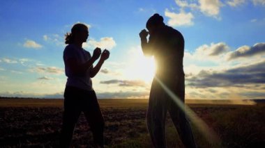 Spor ve eğlence sektörü. Baba oğul gün batımında antrenman yapıyor. İki baba ve oğul doğada boks yapıyor. Spor, sağlık, eğlence kavramı. 