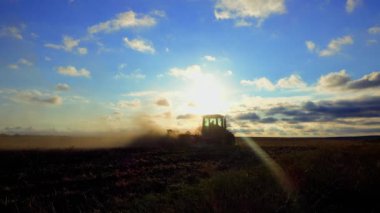 Tarım. Traktör gün batımında tarlayı sürüyor. Buğday hasadından sonra arazi ekimi. Tarlaların mekanize ekimi. 