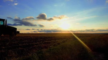 Tarım. Traktör gün batımında tarlayı sürüyor. Buğday hasadından sonra arazi ekimi. Tarlaların mekanize ekimi. 