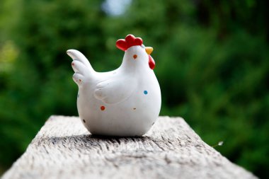 Clay figurine of a chicken on different backgrounds. Handmade clay white chicken. The concept of art, decorative toys, sculpture. 