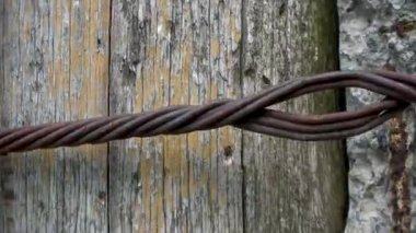 Old wooden electric pole. A wooden pole tied with iron wire. Texture of old wood, concrete and rusty wire. Camera movement.