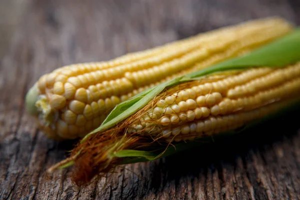 Corn cobs lie on a wooden table. Ripe corn lies on a textured old table. The concept of food, vegetarianism, world nutrition problems. 