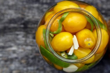 Fresh organic yellow tomatoes in a jar. Organic non-GMO yellow tomatoes on a canning table. The concept of health, non-GMO products, clean ecological food. 