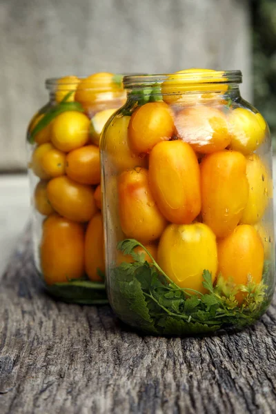 Fresh organic yellow tomatoes in a jar. Organic non-GMO yellow tomatoes on a canning table. The concept of health, non-GMO products, clean ecological food.