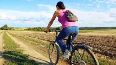 Young happy woman on a bike in the field. The girl takes a bike ride in nature. The concept of happiness, recreation, sports, nature. 