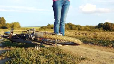 Young happy woman on a bike in the field. Girl rides a bike in nature. Close-up portrait, view from behind the grass. Camera movement.Concept of happiness, recreation, sports, nature. 