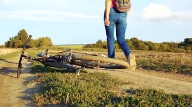 Young happy woman on a bike in the field. Girl rides a bike in nature. Close-up portrait, view from behind the grass. Camera movement.Concept of happiness, recreation, sports, nature. 