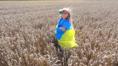 Little girl with the Ukrainian flag in the field. Child girl with the flag of Ukraine in the field of wheat. The concept of freedom, independence, peace. 