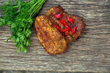 Meat steak cooked on the barbecue. Grilled fresh meat steak with spices and red pepper. Ready steak on the table with tomatoes and peppers. The concept of food, restaurants, traditional cuisine. 