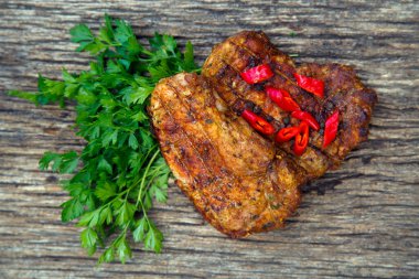 Meat steak cooked on the barbecue. Grilled fresh meat steak with spices and red pepper. Ready steak on the table with tomatoes and peppers. The concept of food, restaurants, traditional cuisine. 